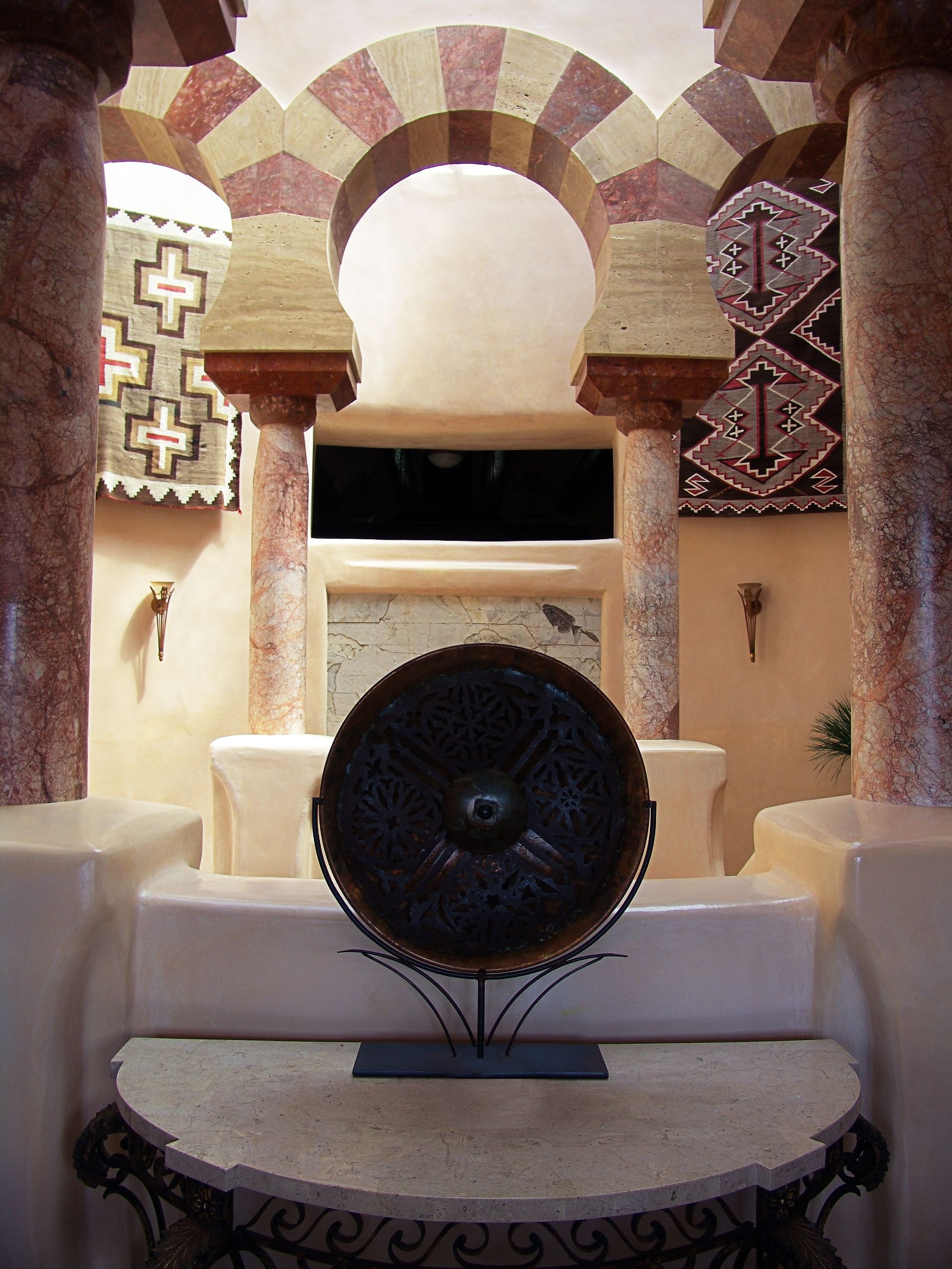 A round object on a stand in a room with columns