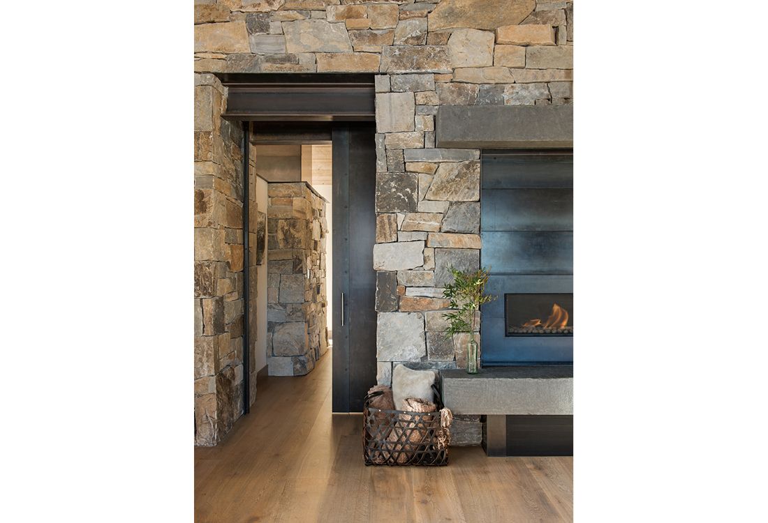 A living room with a stone wall and a fireplace.
