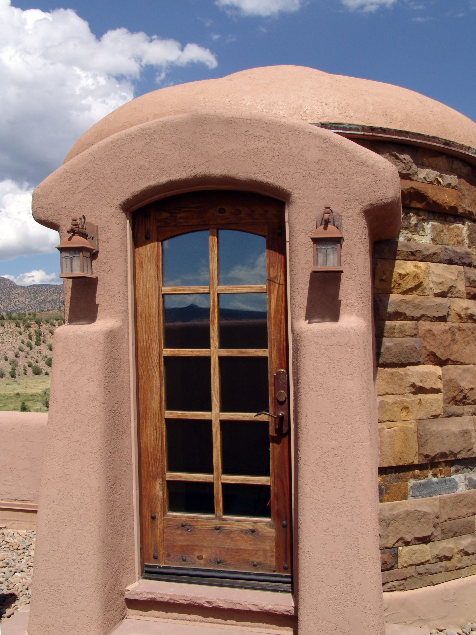 A brick building with a wooden door and two lights on the side