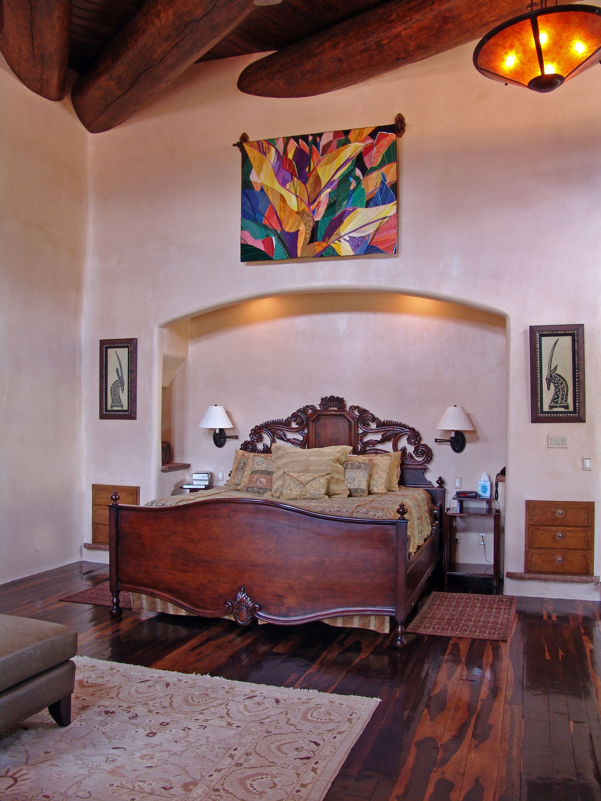 A bedroom with a painting on the wall above the bed