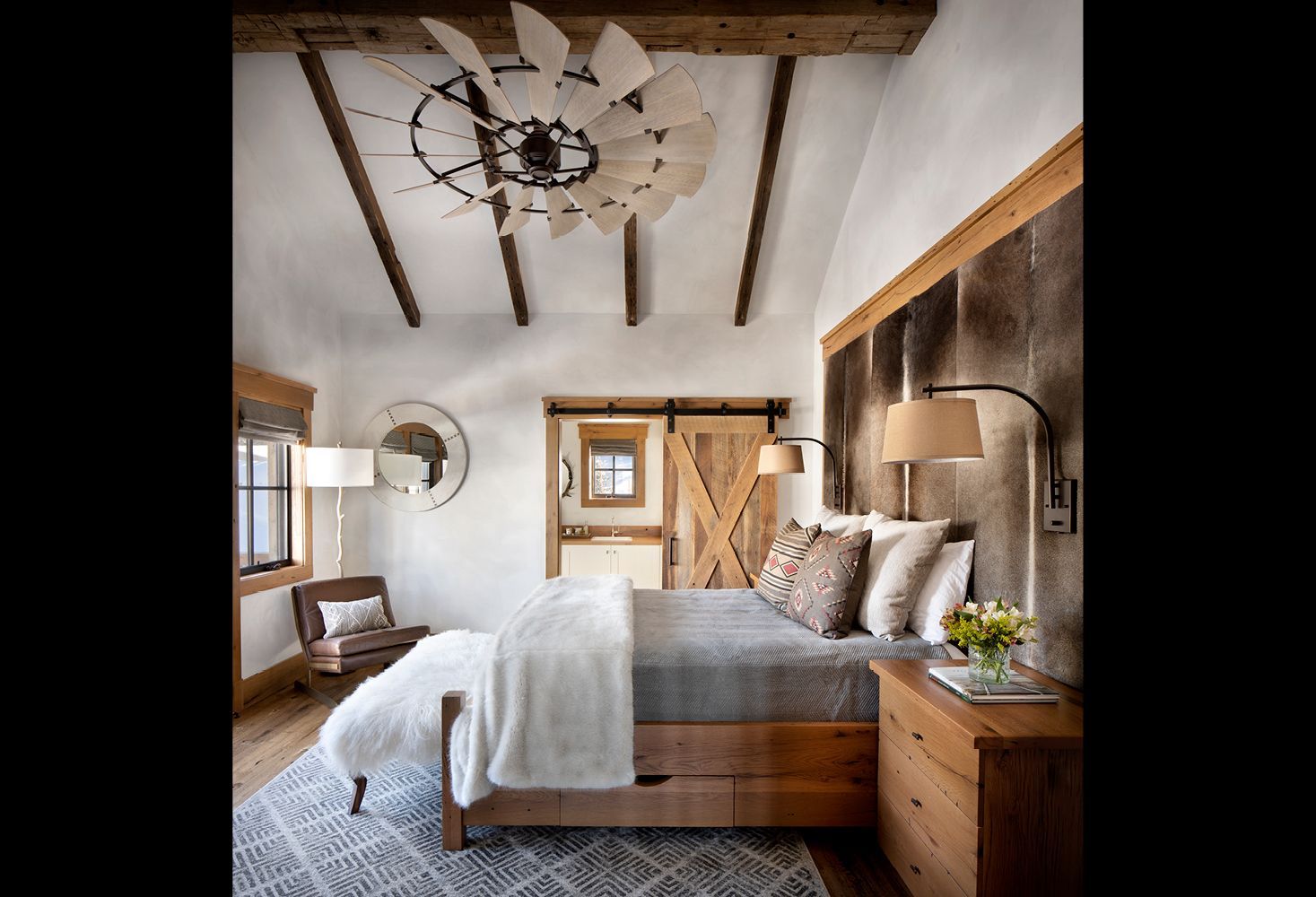 A bedroom with a bed , nightstand , chair and sliding barn door.
