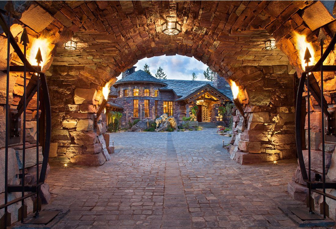 A stone archway leading to a large house