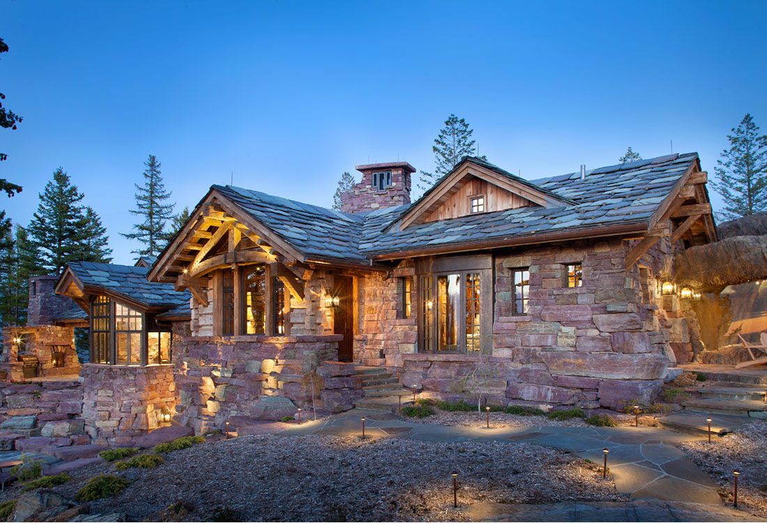 A large stone house with a slate roof is lit up at night.