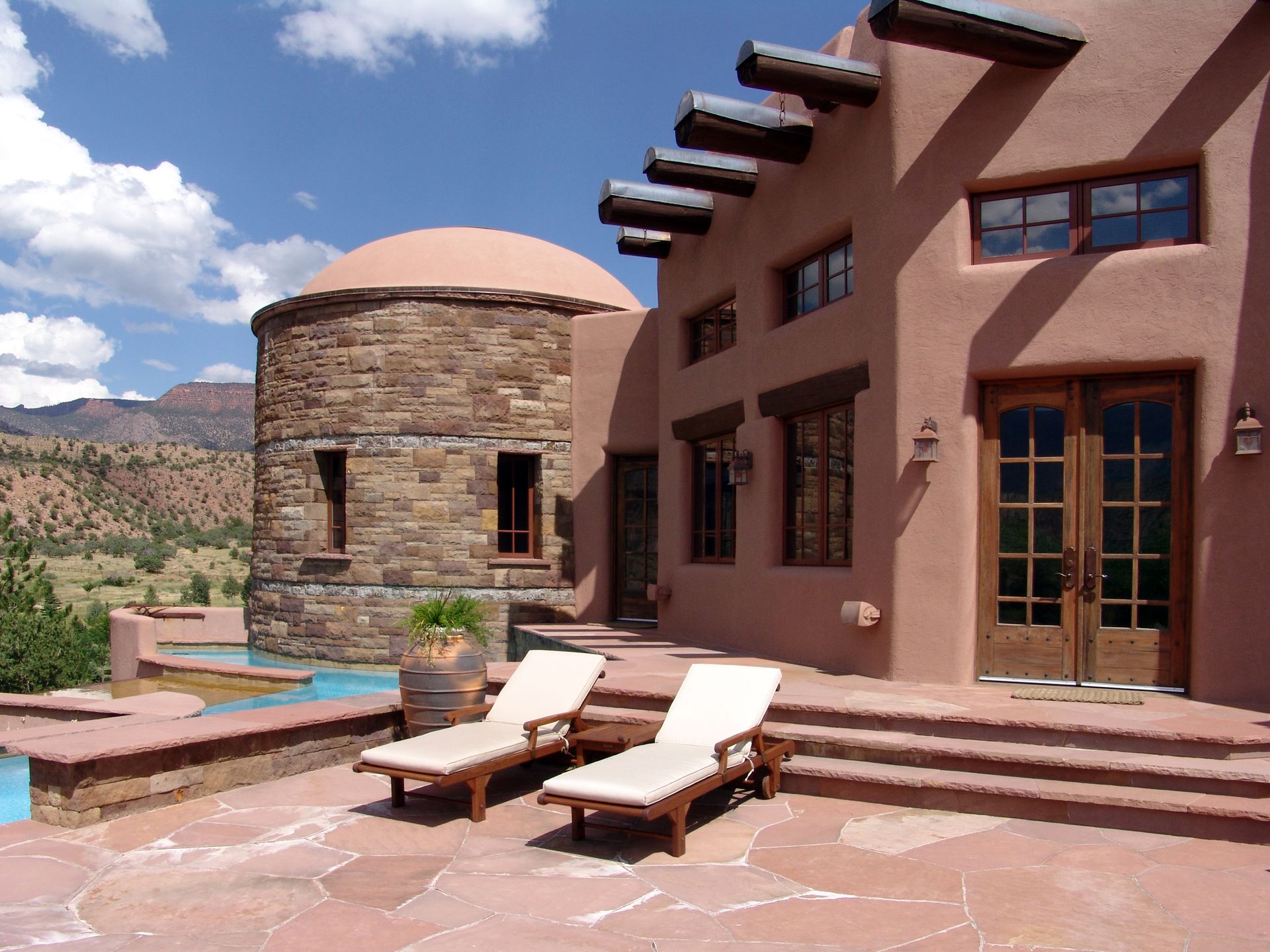 Two lounge chairs sit on a patio in front of a large building