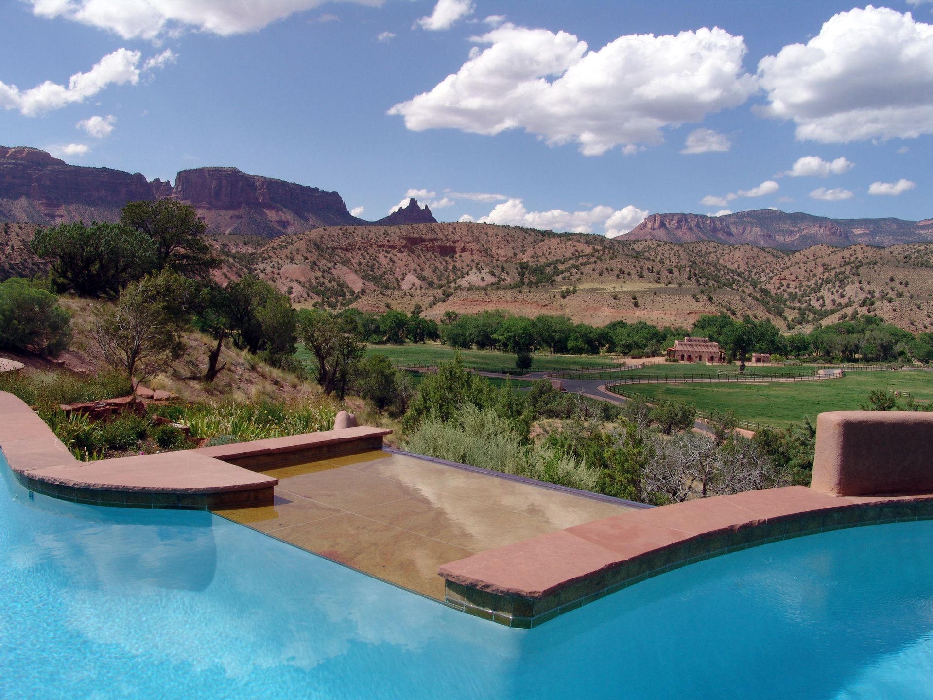 A swimming pool with a view of a golf course and mountains