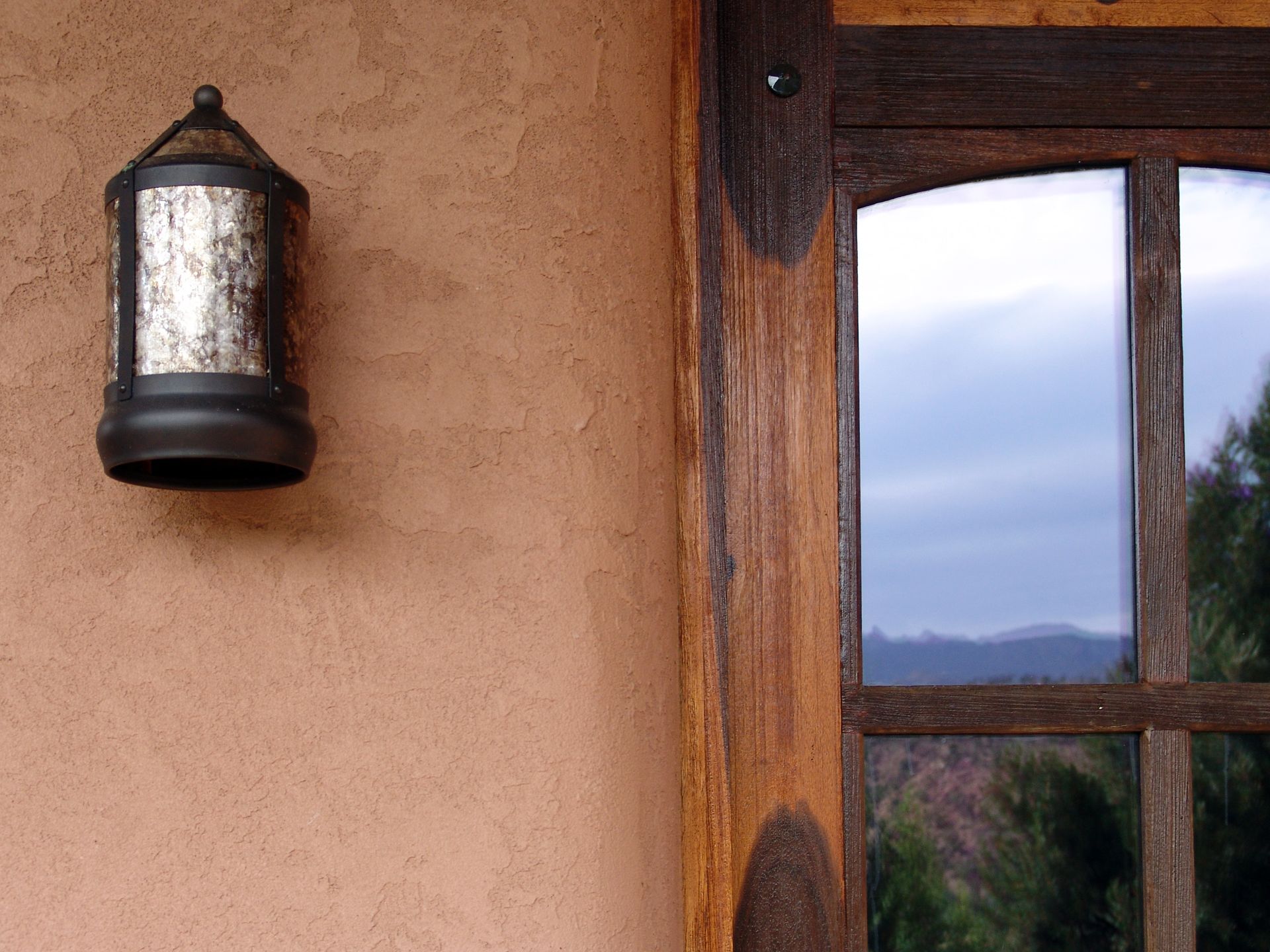 A lamp is hanging on a wall next to a window.