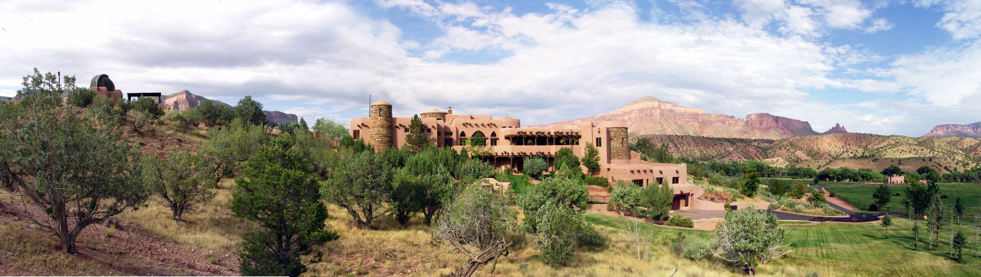 A large building is sitting on top of a hill surrounded by trees.