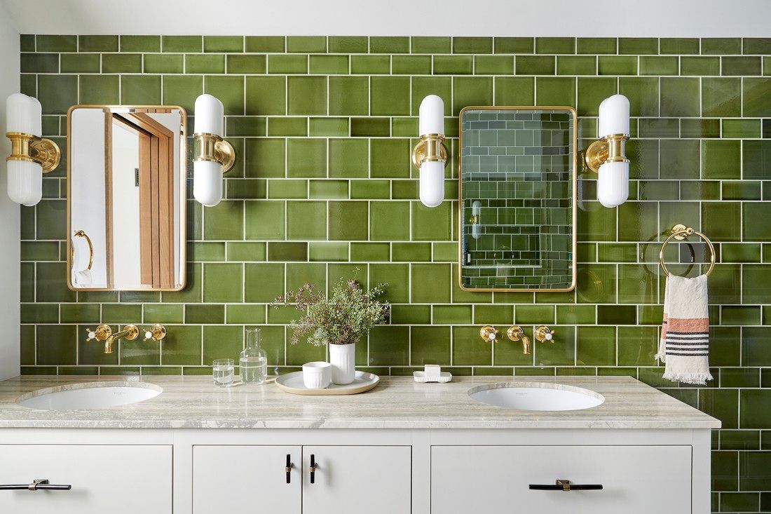 A bathroom with green tiles and two sinks.