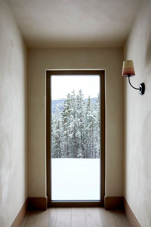 A hallway with a large window and a lamp on the wall.