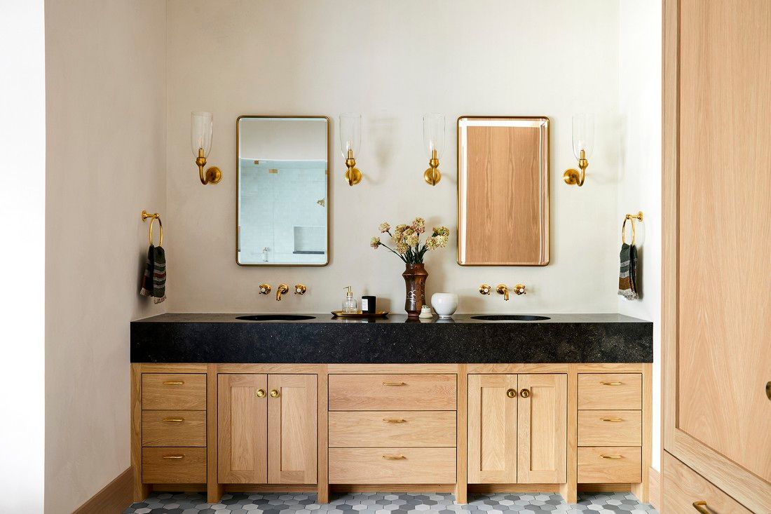 A bathroom with two sinks , a mirror and wooden cabinets.