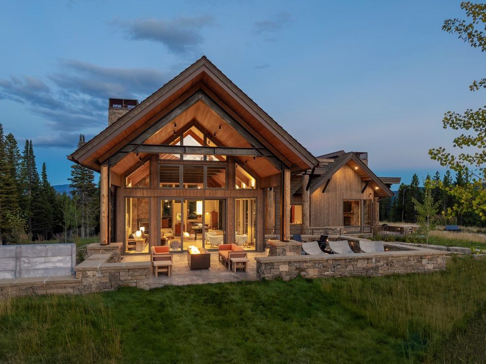 A large house with a lot of windows is sitting in the middle of a grassy field.