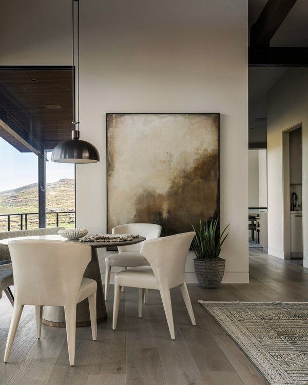 A dining room with a table and chairs and a large painting on the wall.