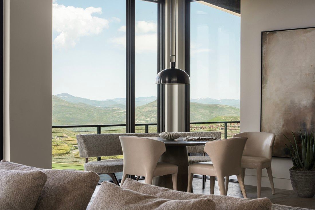 A living room with a couch , chairs and a table with a view of the mountains.