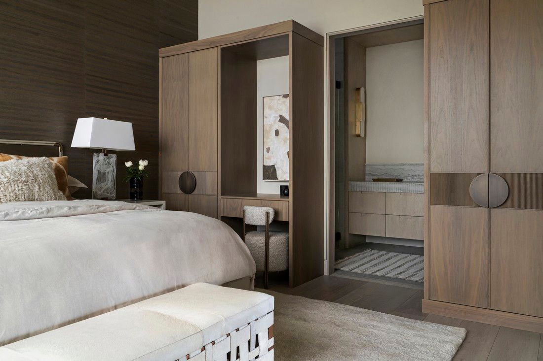 A bedroom with a large bed , a bench , a lamp , and a bathroom.