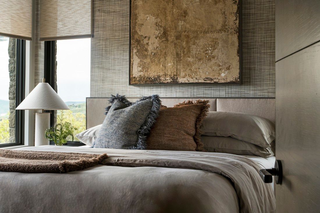 A bedroom with a bed , lamp , and painting on the wall.