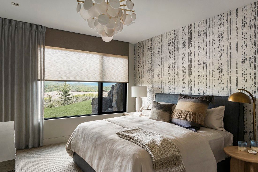 A bedroom with a large bed , two windows and a chandelier.