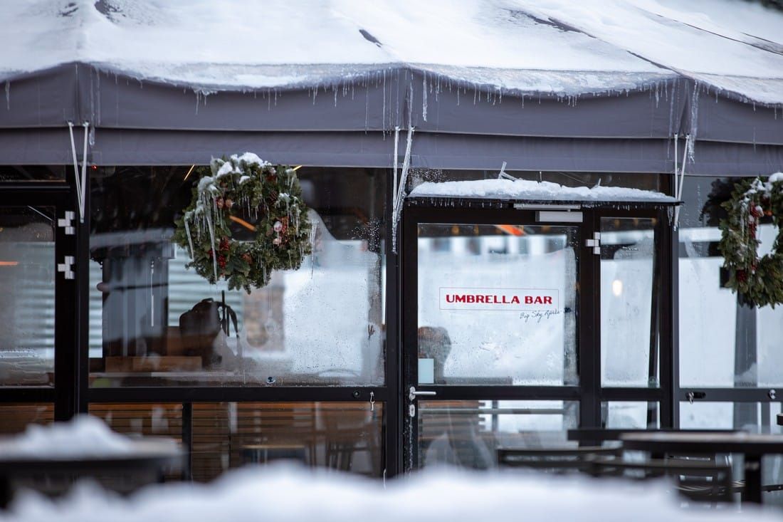 A snowy restaurant with a sign that says umbrella bar