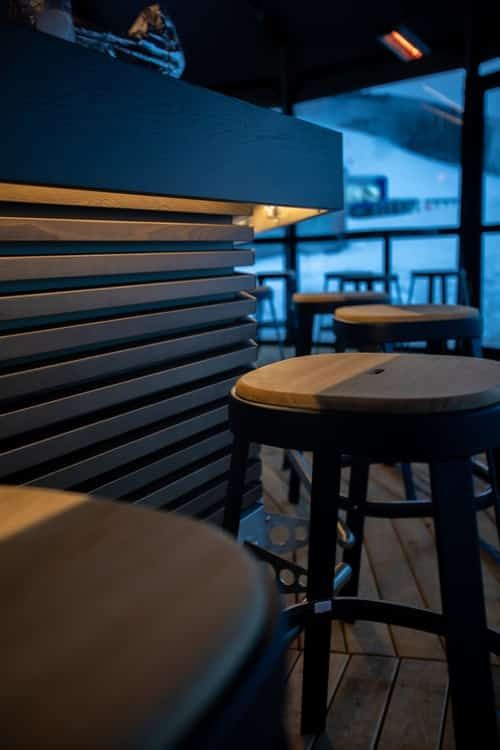 A row of stools are sitting in front of a bar in a restaurant.