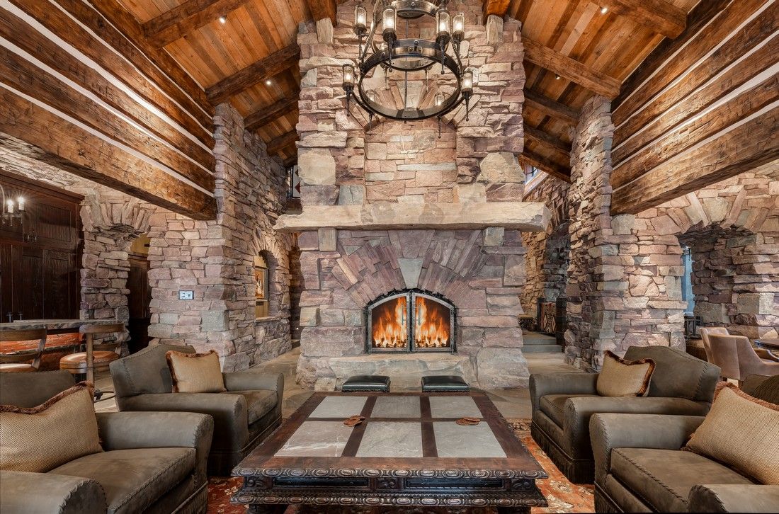 A living room in a log cabin with a large stone fireplace.