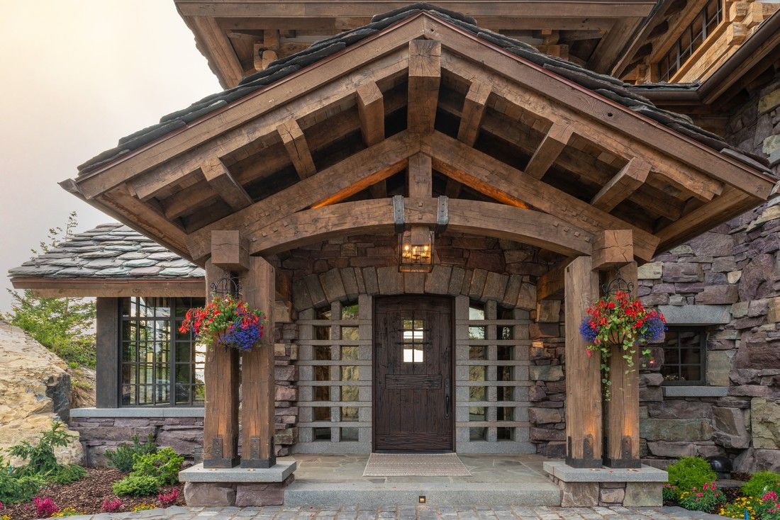 A large stone house with a wooden porch and a wooden roof.