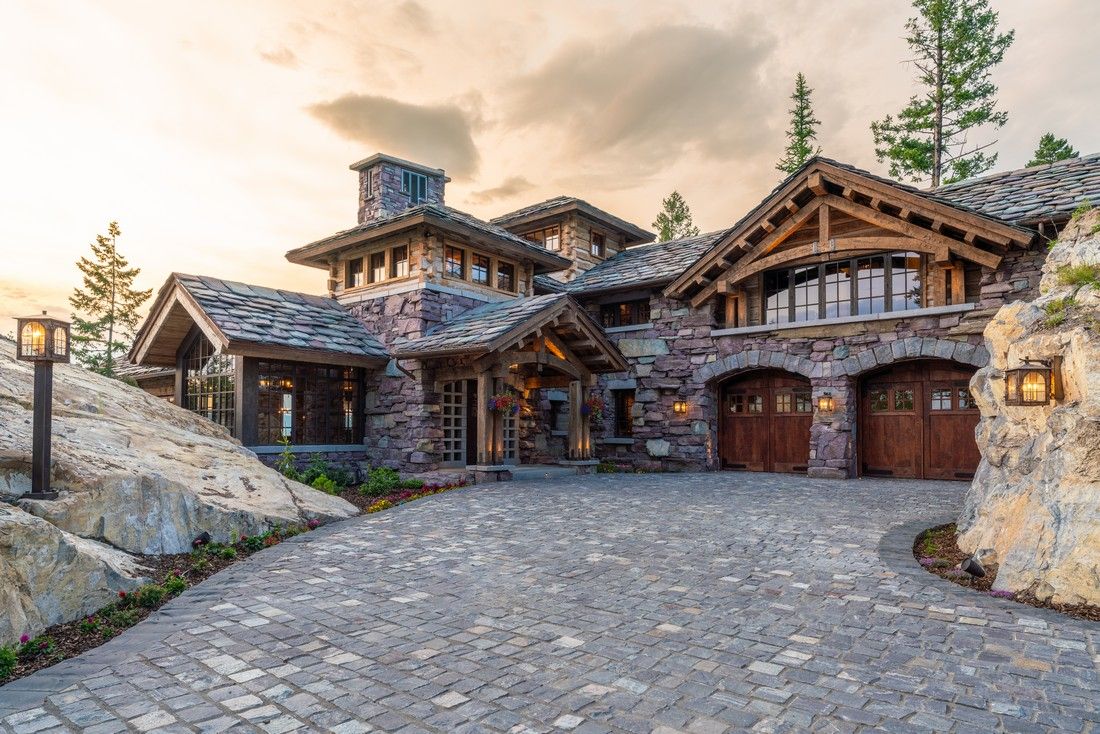 A large stone house with a cobblestone driveway leading to it.
