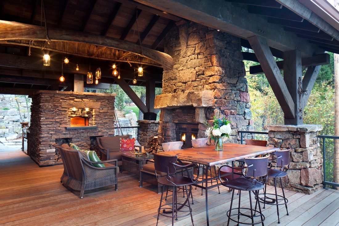 A wooden deck with a table and chairs and a fireplace.