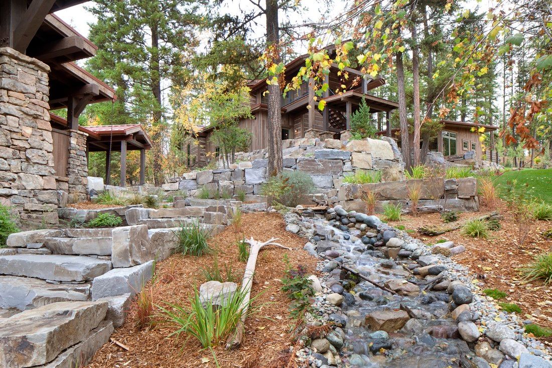 There is a stream running through the woods in front of a house.