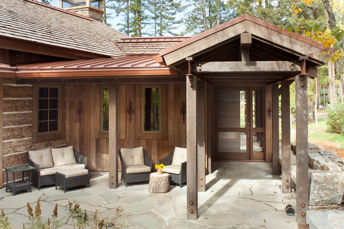 A wooden house with a porch with chairs and a table