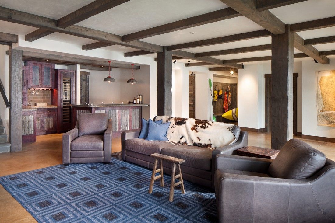A living room with a couch , chairs , and a blue rug.