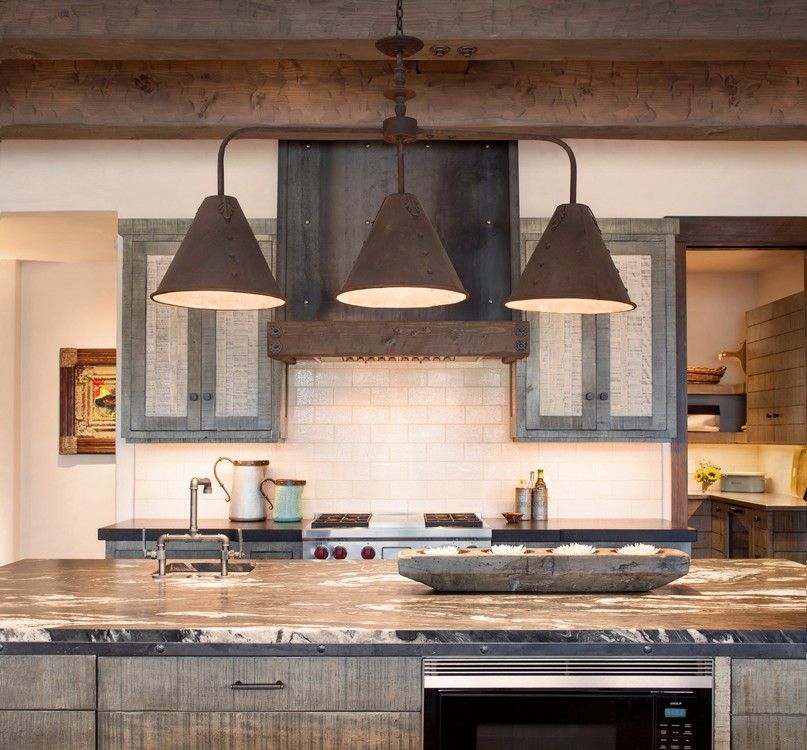 A kitchen with three lamps hanging from the ceiling