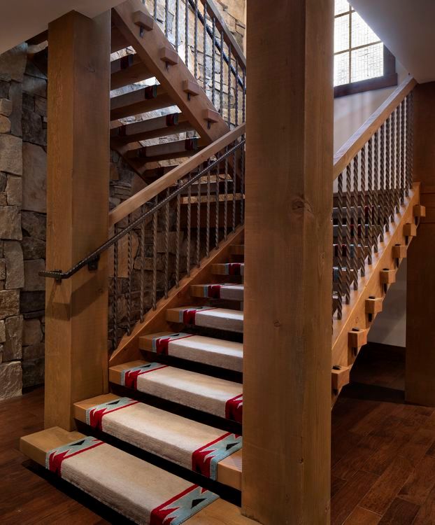 A wooden staircase with a metal railing and carpeted steps