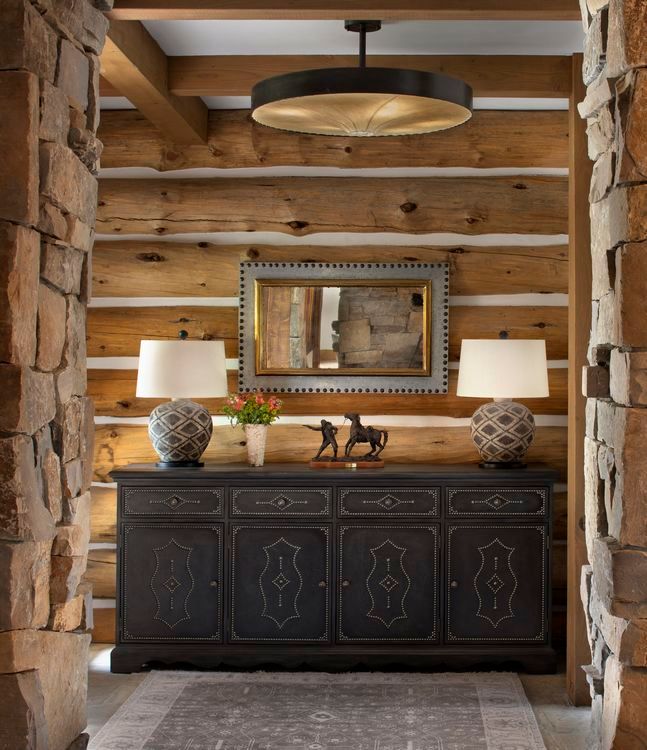 A hallway in a log cabin with a dresser and lamps