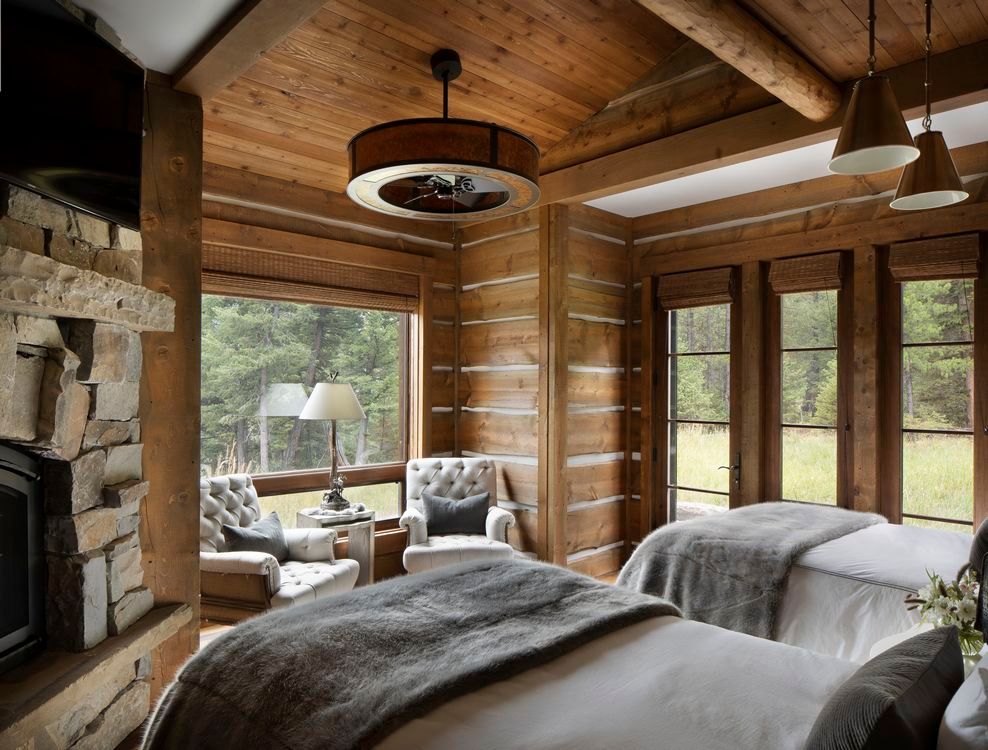 A bedroom in a log cabin with two beds and a fireplace.