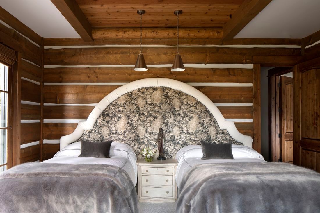 A bedroom with two beds and a wooden headboard