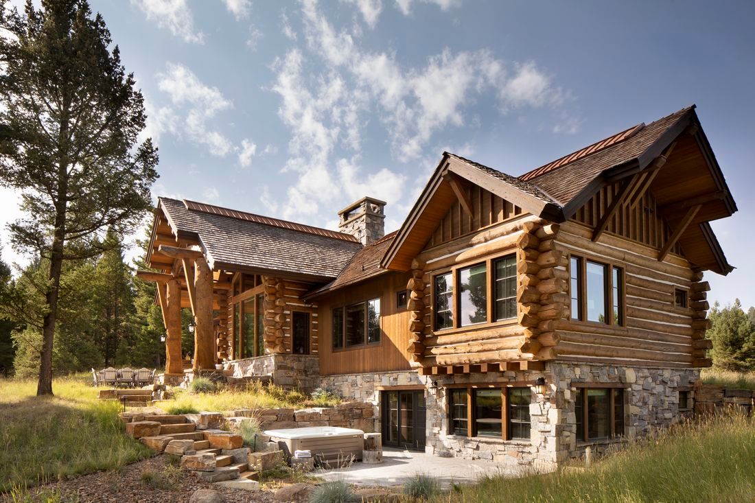 A large log cabin is sitting in the middle of a grassy field.