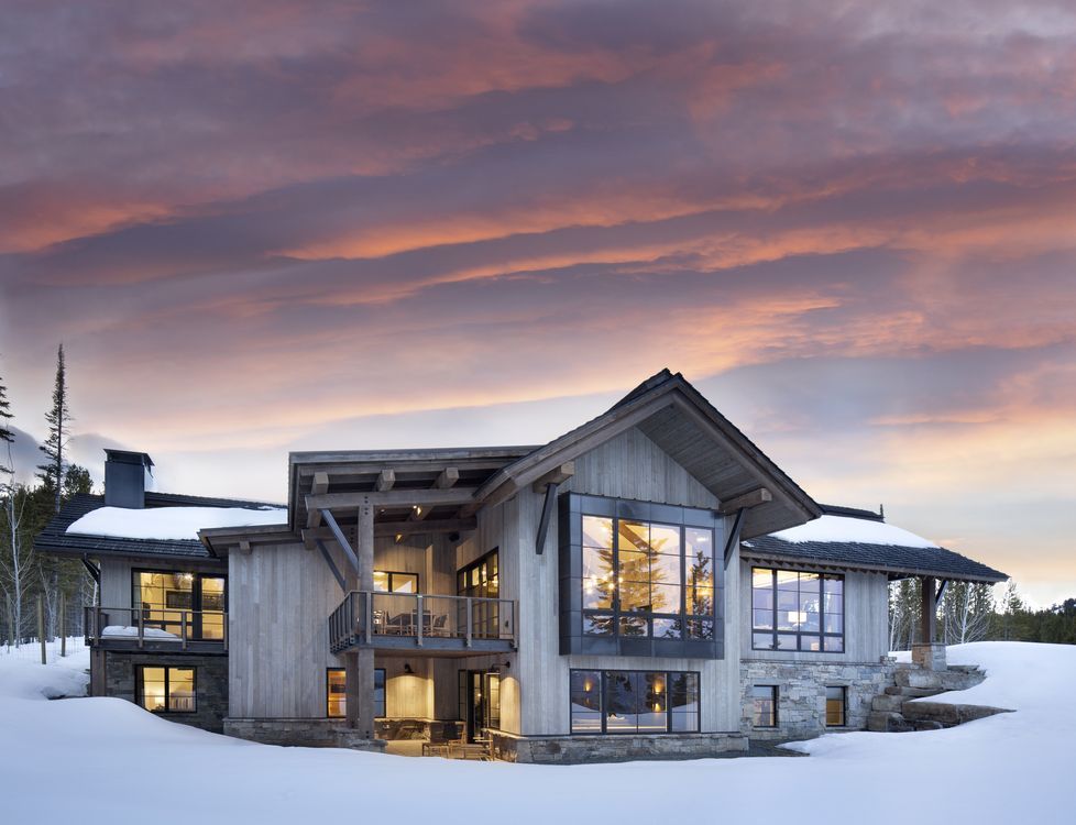 A large house is sitting on top of a snow covered hill.