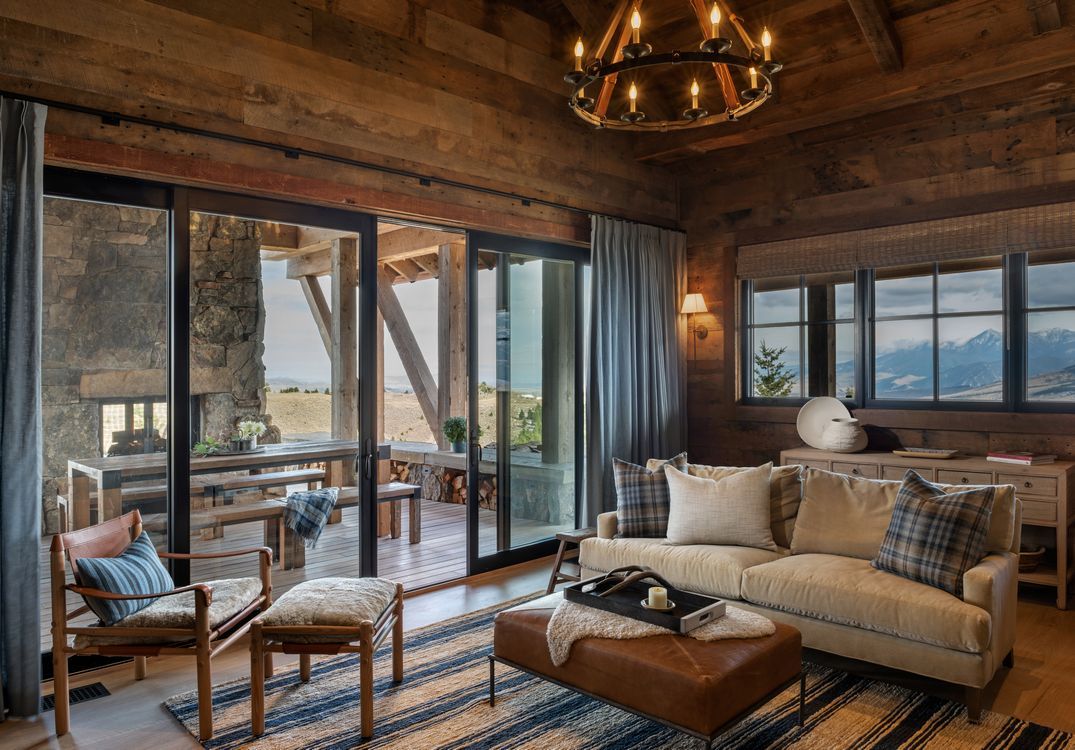 A living room with a couch , chairs , ottoman and sliding glass doors.