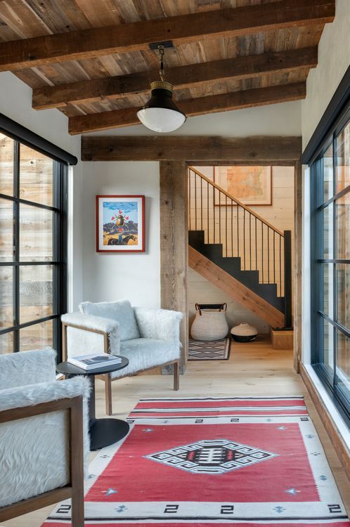 A living room with a chair , rug and stairs.