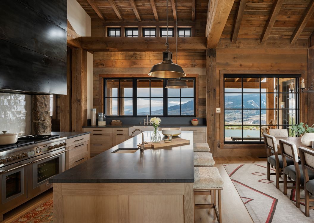 A kitchen in a log cabin with a large island in the middle.