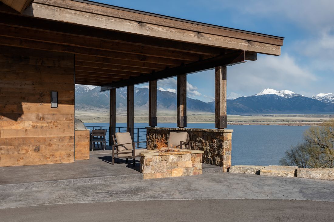 A house with a porch overlooking a lake with mountains in the background.