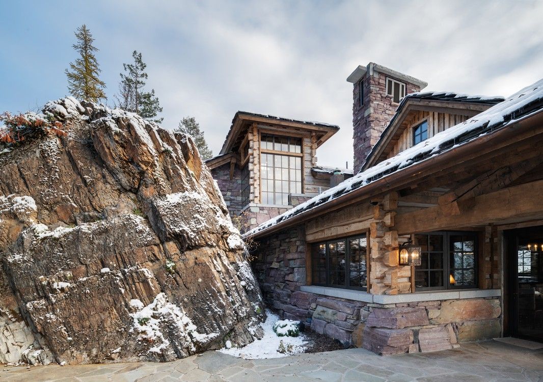 A large house is sitting on top of a snow covered mountain.