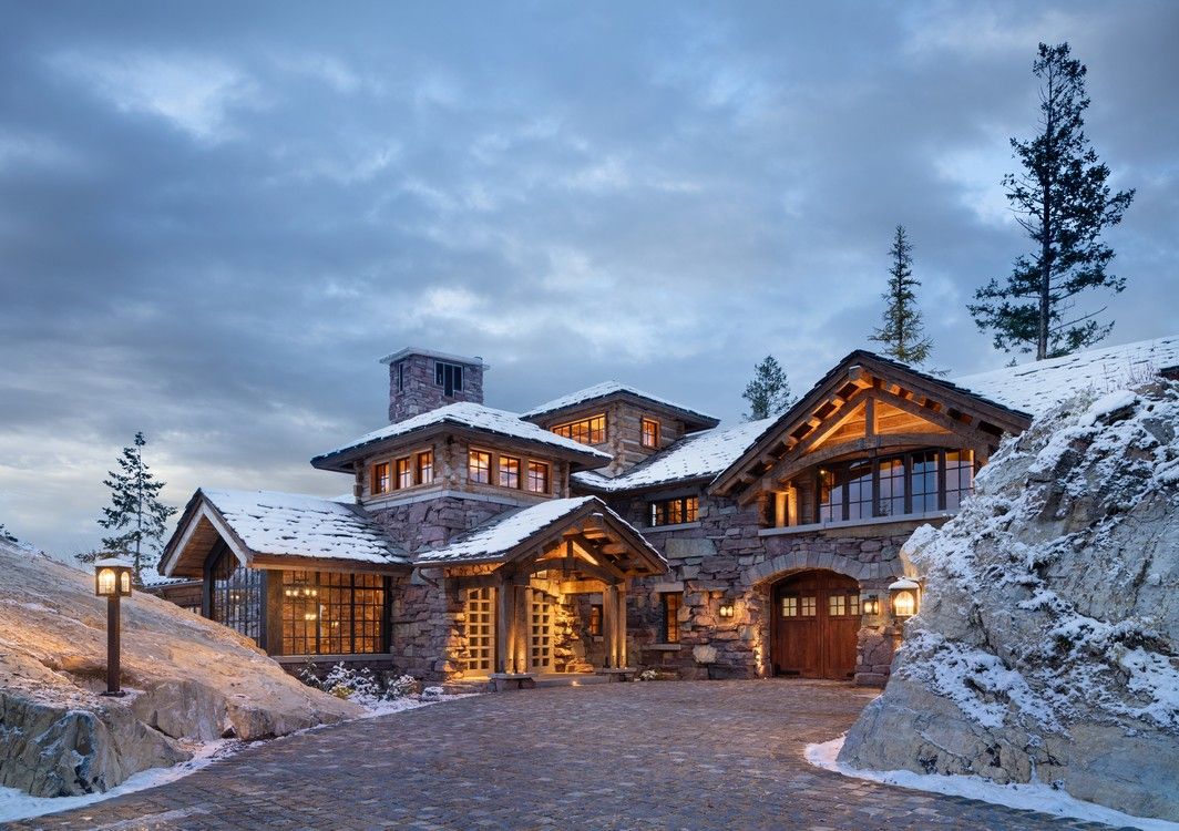 A large house is sitting on top of a snow covered hill.