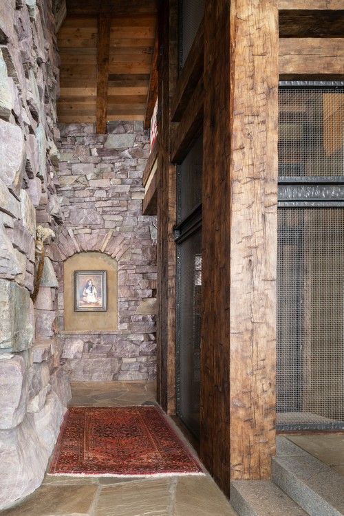 A hallway with a stone wall , wooden beams , and a rug.