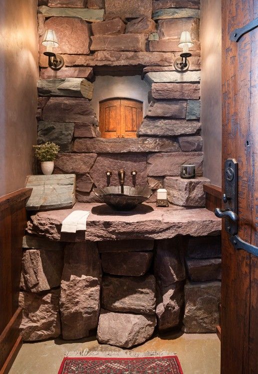 A bathroom with a stone sink and a stone wall.