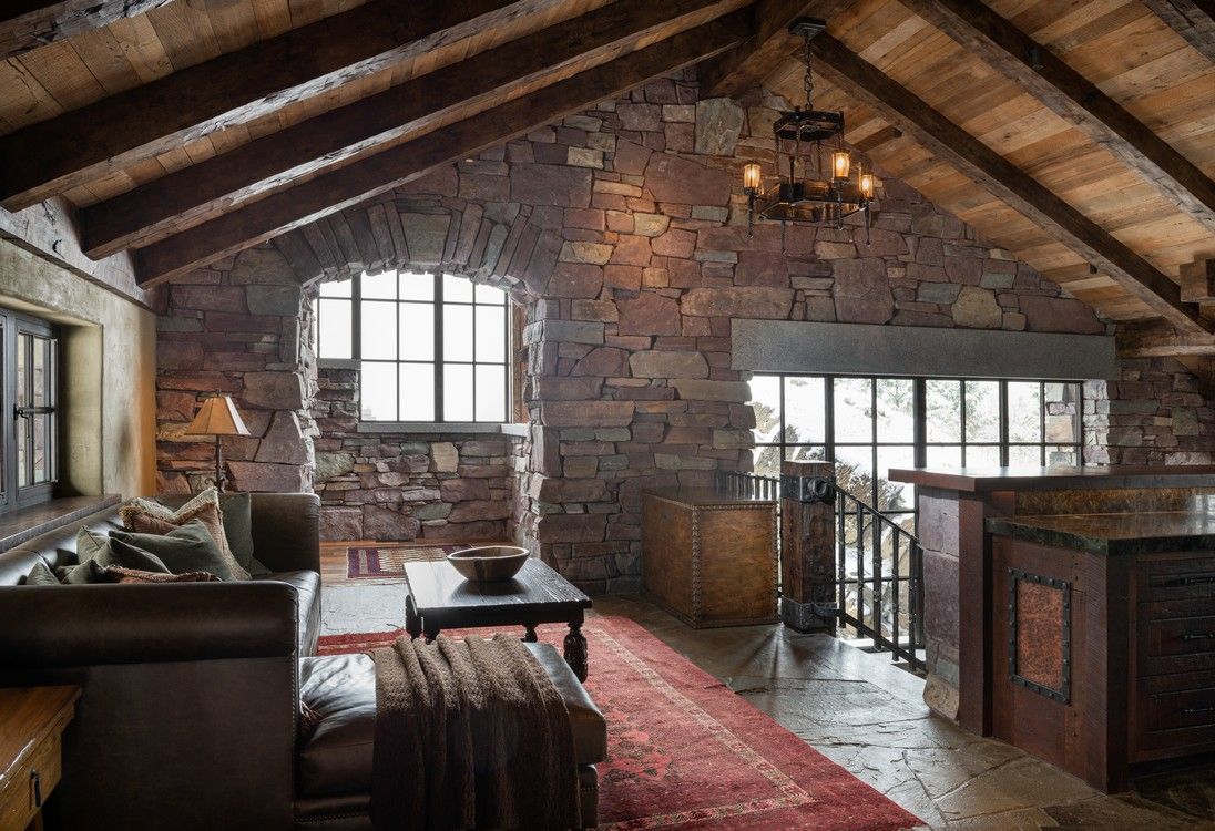 A living room with a stone wall and a wooden ceiling