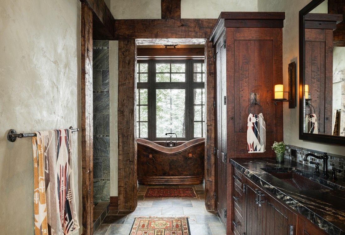 A bathroom with a tub , sink , mirror and window.