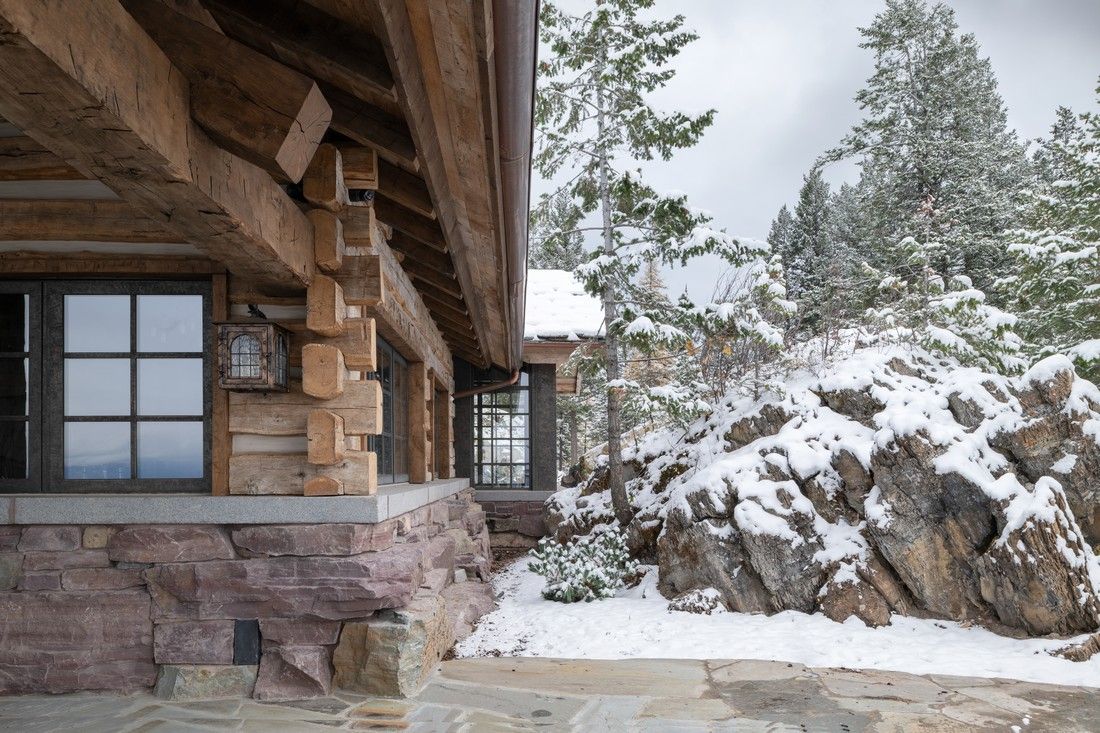 A log cabin is sitting on top of a snow covered hill.