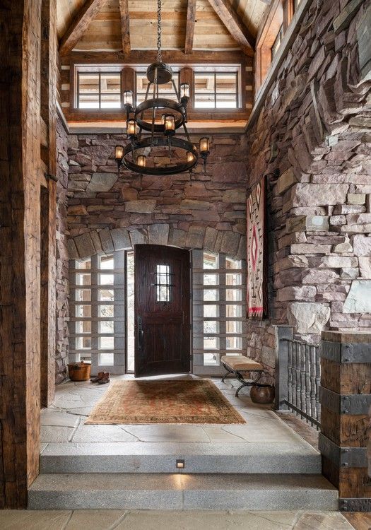 A hallway with a wooden door and a chandelier hanging from the ceiling.