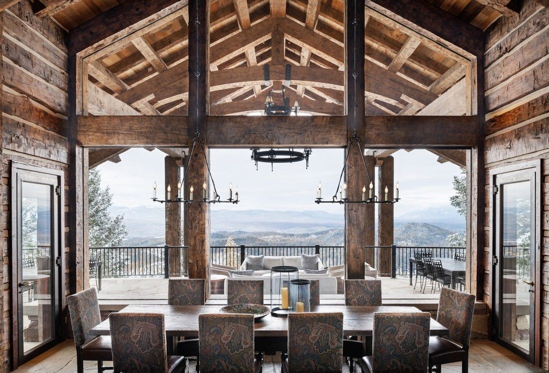 A dining room in a log cabin with a large table and chairs.
