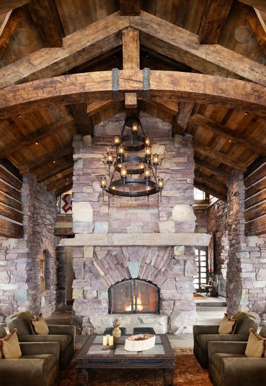 A living room with a large stone fireplace and wooden beams